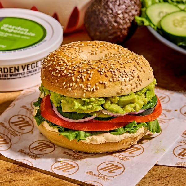 A sesame bagel from Manhattan Bagel, filled with avocado, tomato, red onion, lettuce, and cream cheese.